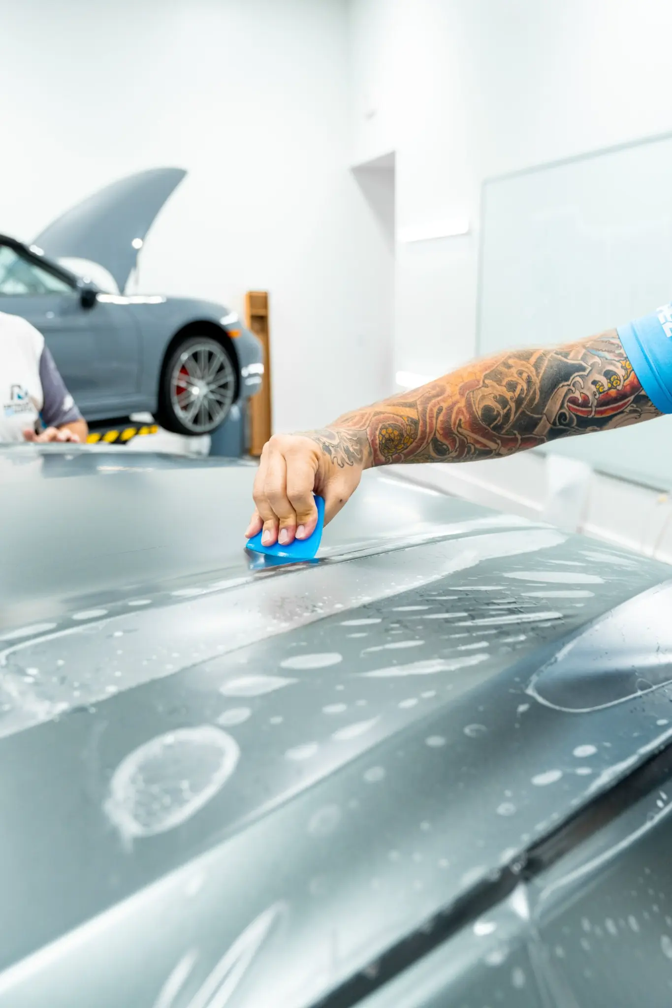 Installer applying PPF to hood of a grey car
